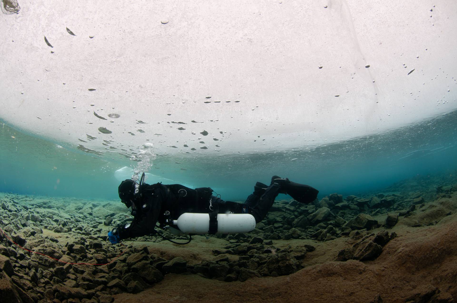 Sidemount diver reeling in his line after a icedive in lake Thingvellir.