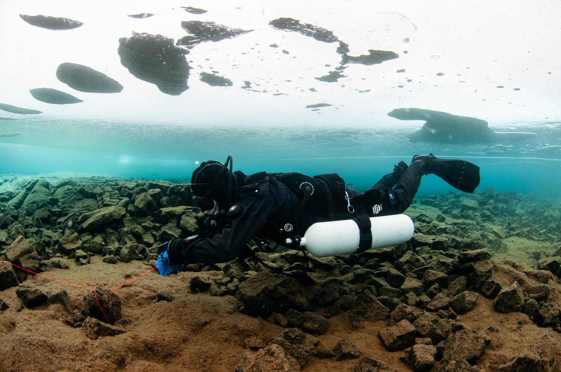 Sidemount diver reeling in his line after a icedive in lake Thingvellir.